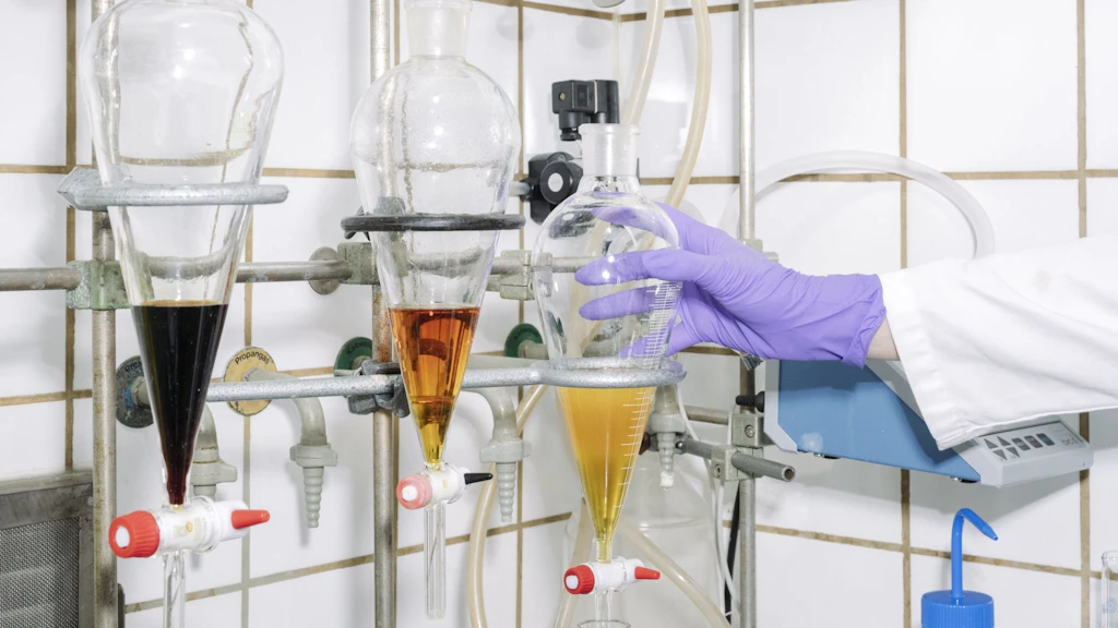 Eine Hand im Laborkittel führt Chemiearbeiten an Gefässen in einem Labor durch.