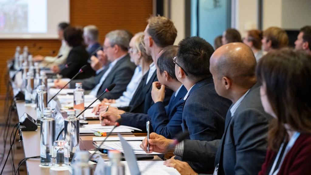 Plusieurs personnes sont assises autour d'une table de réunion et regardent la présentation.